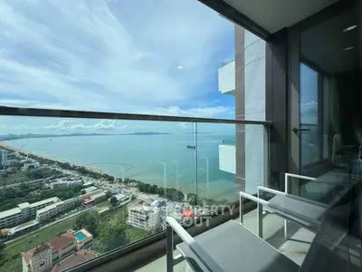 Stunning ocean view from a modern balcony with glass railing and seating area.