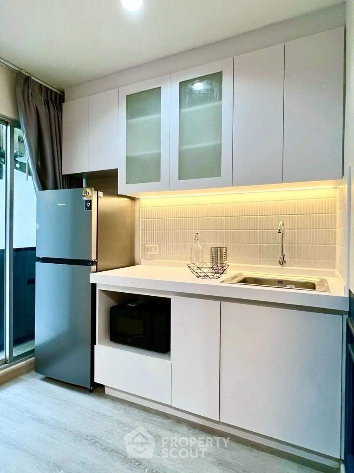 Modern kitchen with sleek cabinetry, built-in microwave, and stylish lighting.