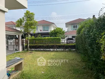 Charming suburban garden with lush greenery and modern houses in the background.