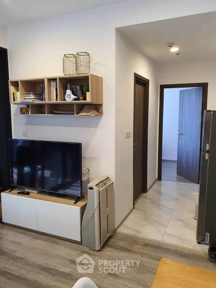 Modern living room with sleek TV setup and stylish shelving in a cozy apartment.