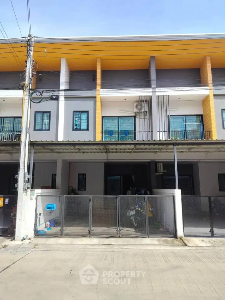 Modern townhouse exterior with balcony and gated entrance