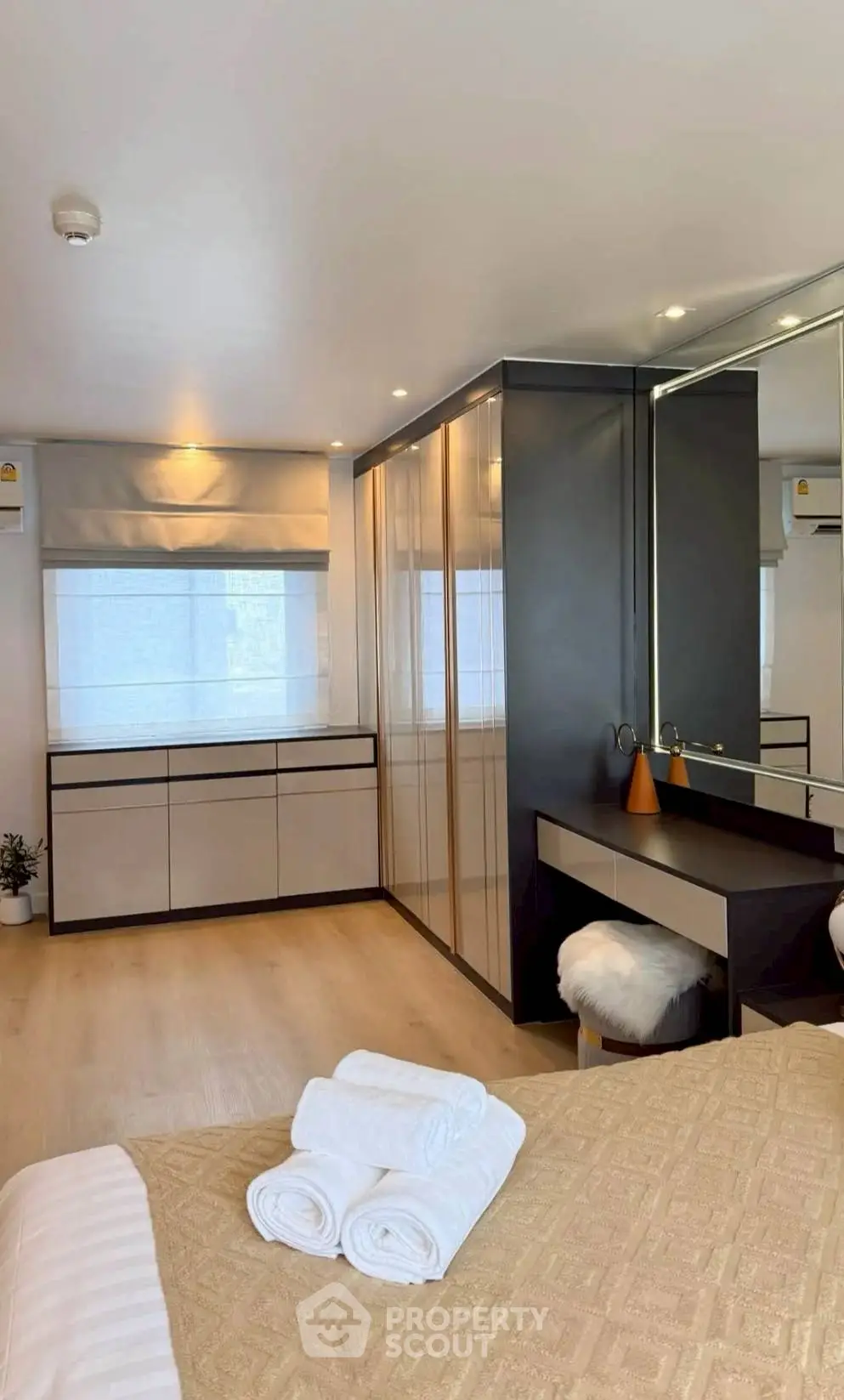 Luxurious bedroom with modern decor and ample natural light, featuring a stylish vanity and elegant furnishings.