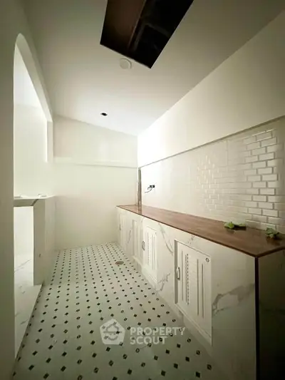 Spacious kitchen with elegant marble flooring and sleek wooden countertops, perfect for modern living.