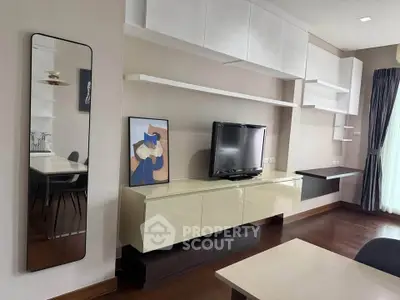 Modern living room with sleek cabinetry and wall-mounted TV, featuring elegant decor and natural light.