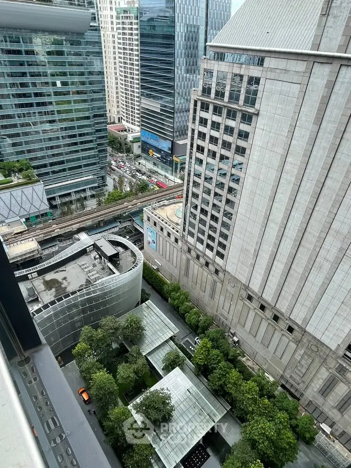 Stunning cityscape view from high-rise balcony overlooking modern skyscrapers and lush greenery.