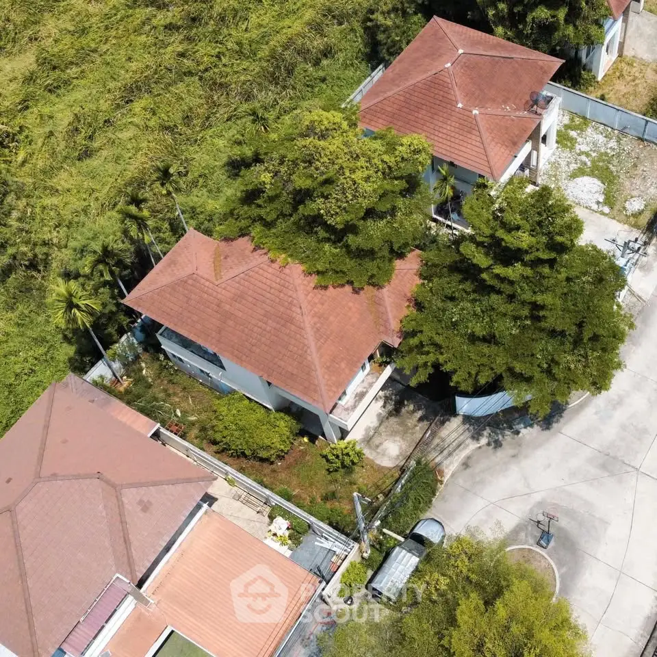 Aerial view of suburban homes with red roofs and lush greenery.