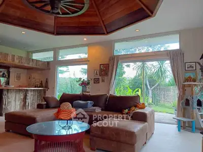 Spacious living room with rustic decor and garden view, featuring large windows and cozy seating area.