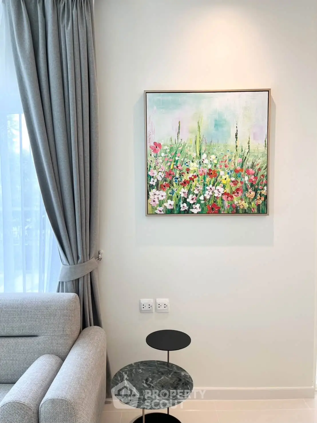 Elegant living room with modern decor and vibrant floral painting, featuring a cozy sofa and stylish side table.