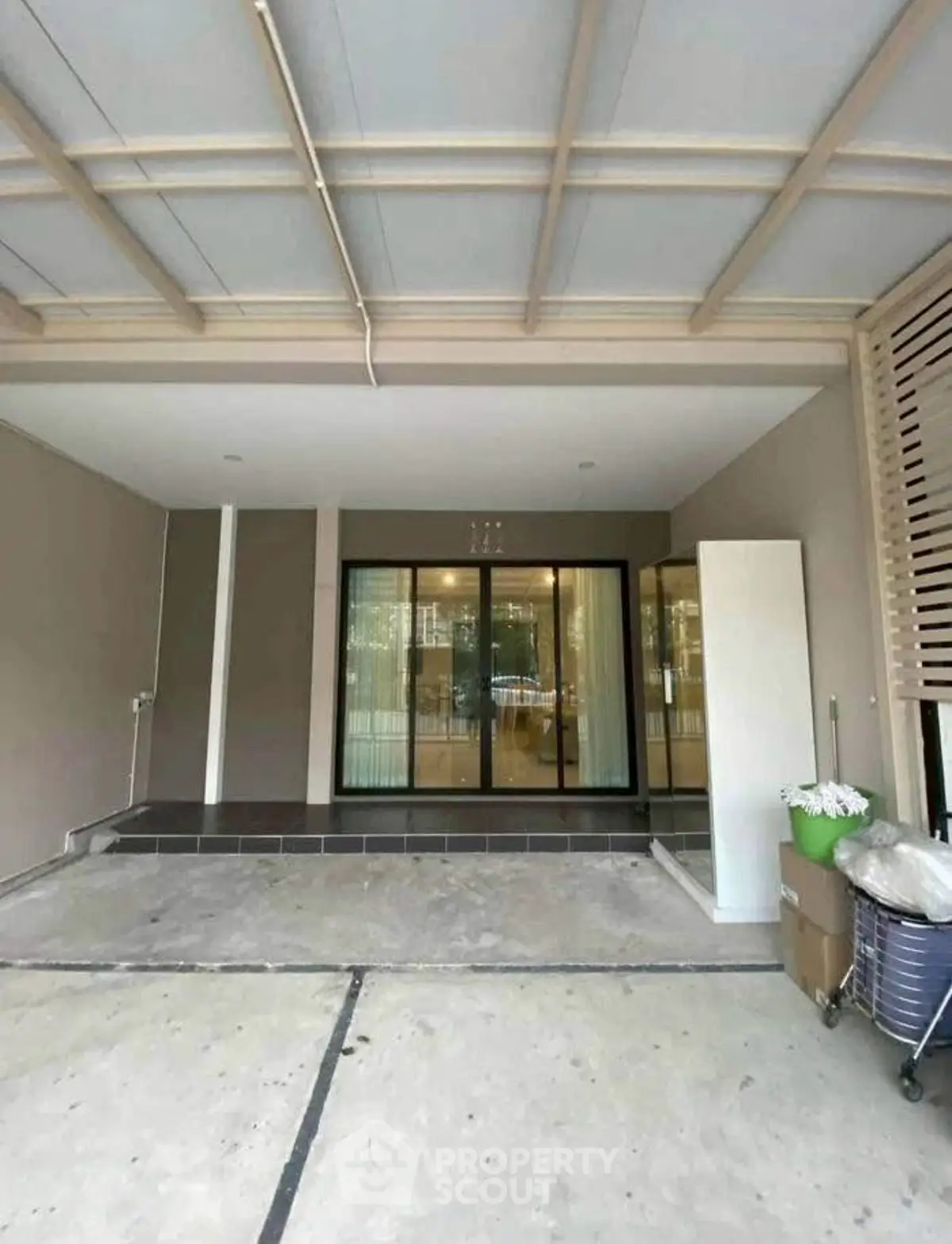 Modern residential entrance with sleek glass doors and covered parking area.