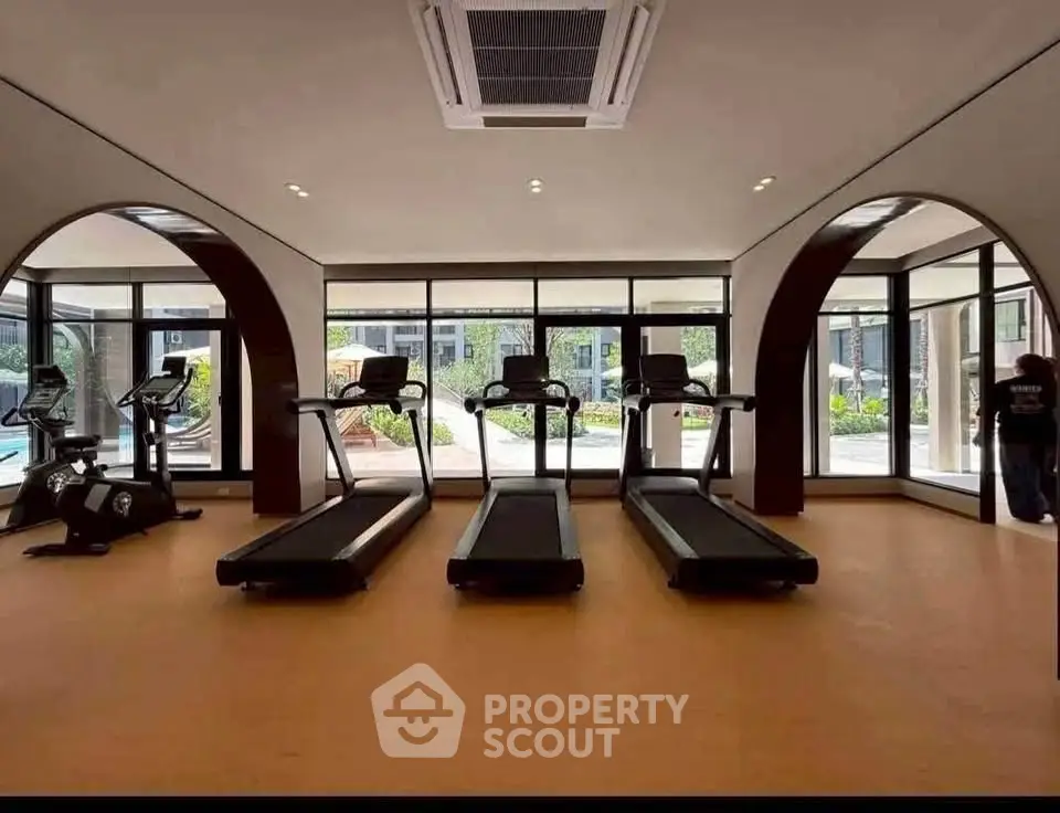 Modern gym with treadmills and large windows in luxury residential building.