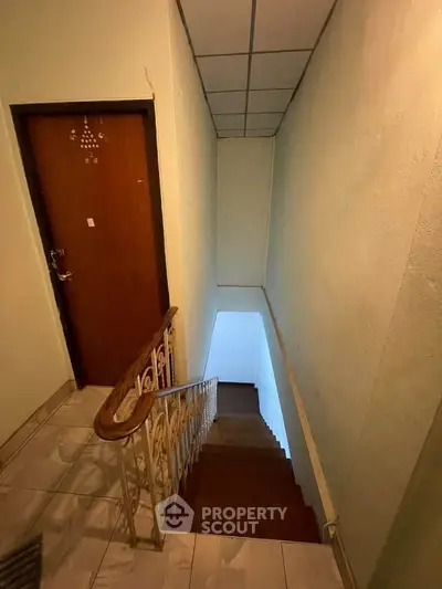 Charming staircase leading to a cozy apartment entrance with elegant railing and tiled flooring.