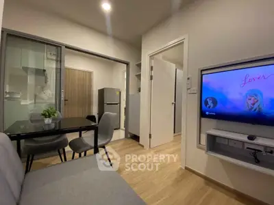 Modern living room with open kitchen and dining area, featuring sleek furniture and stylish decor.