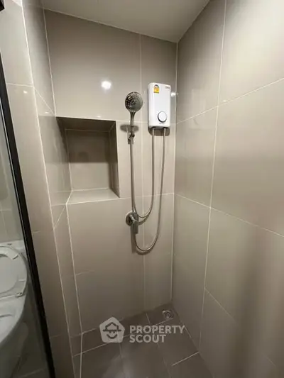Modern bathroom shower area with sleek tiles and built-in shower unit.