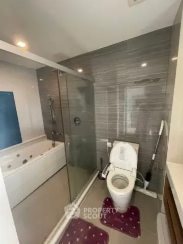 Modern bathroom with glass shower and bathtub in sleek apartment.