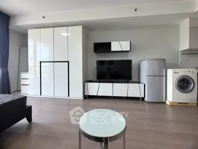 Modern living room with sleek furniture, TV, fridge, and washing machine in a stylish apartment.