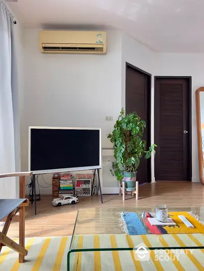 Cozy living room with modern decor and natural light, featuring a stylish TV setup and indoor plant.