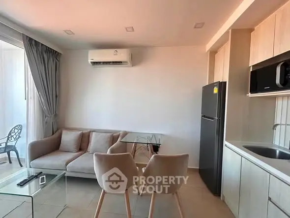 Modern living room with sleek furniture and kitchen appliances in a cozy apartment setting.