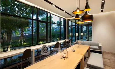 Modern living room with large windows and stylish lighting, offering a serene garden view.