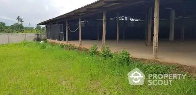 Spacious open-air structure with lush green surroundings ideal for agricultural or storage use.