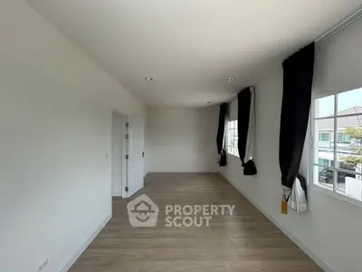 Spacious unfurnished room with wooden flooring and large windows offering natural light.