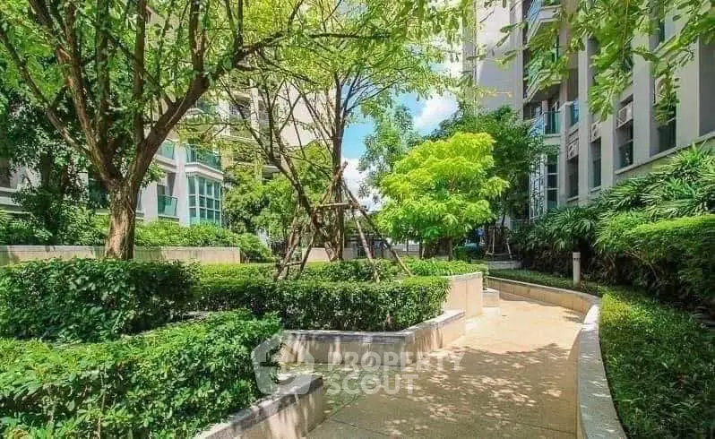 Lush green garden pathway in modern residential complex, perfect for relaxation and outdoor activities.