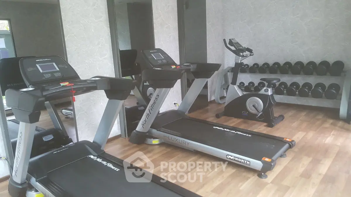 Modern gym with treadmills and exercise bike in luxury apartment complex.