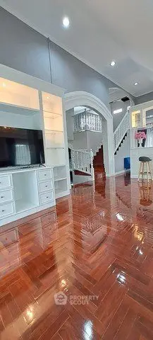 Spacious living room with glossy wooden floors and elegant staircase