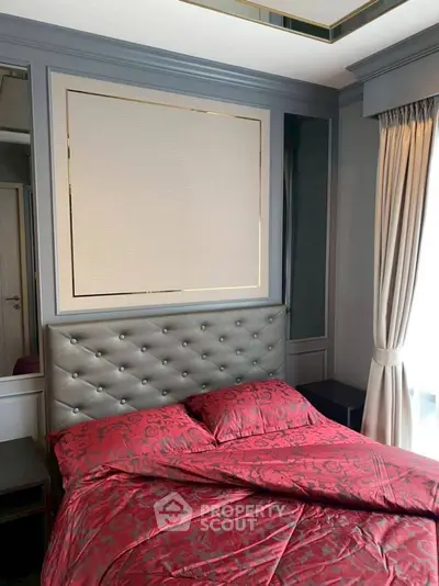 Luxurious bedroom with elegant red bedding and tufted headboard, featuring stylish wall paneling and natural light.