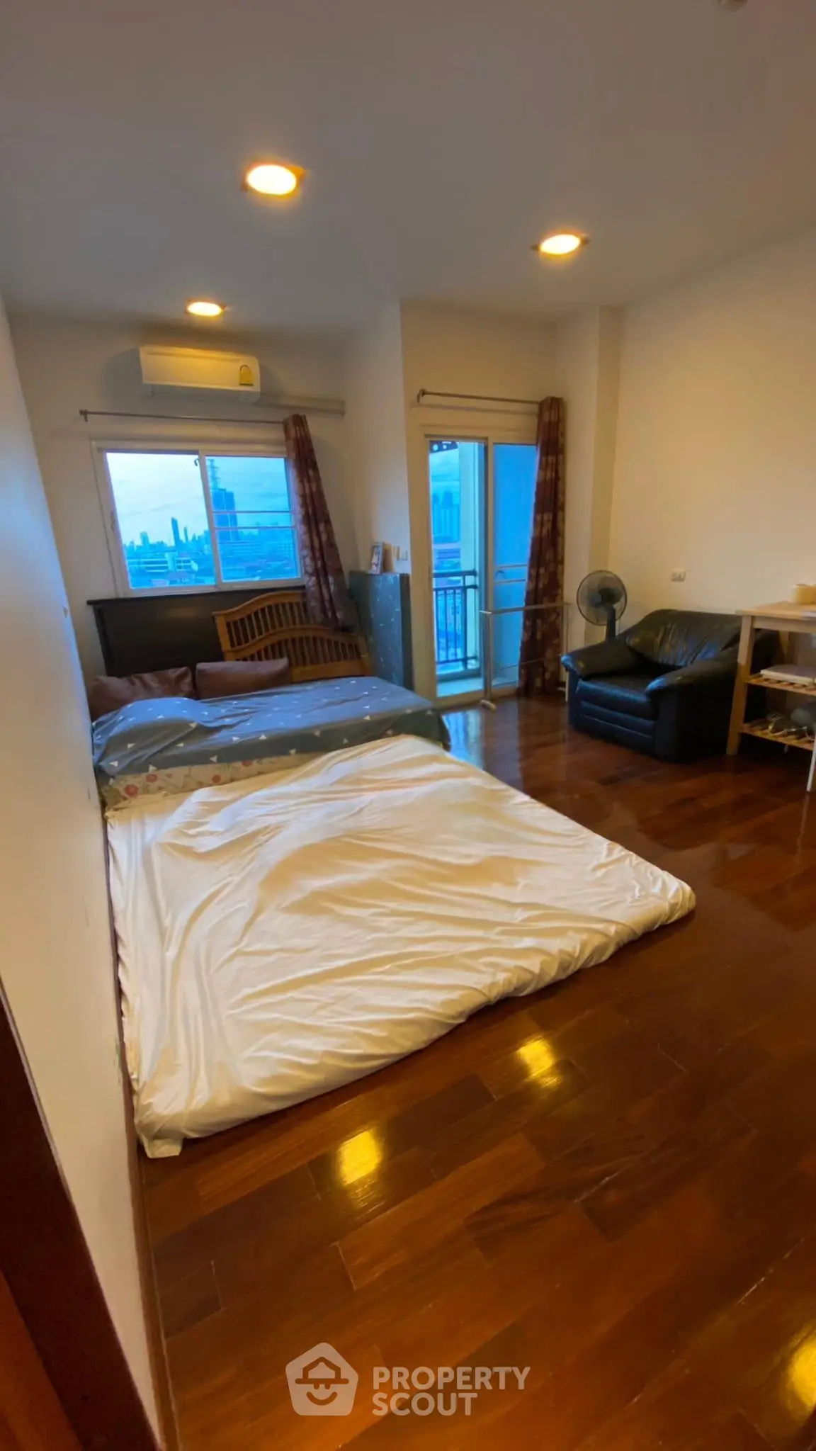 Cozy bedroom with wooden flooring and balcony access in modern apartment