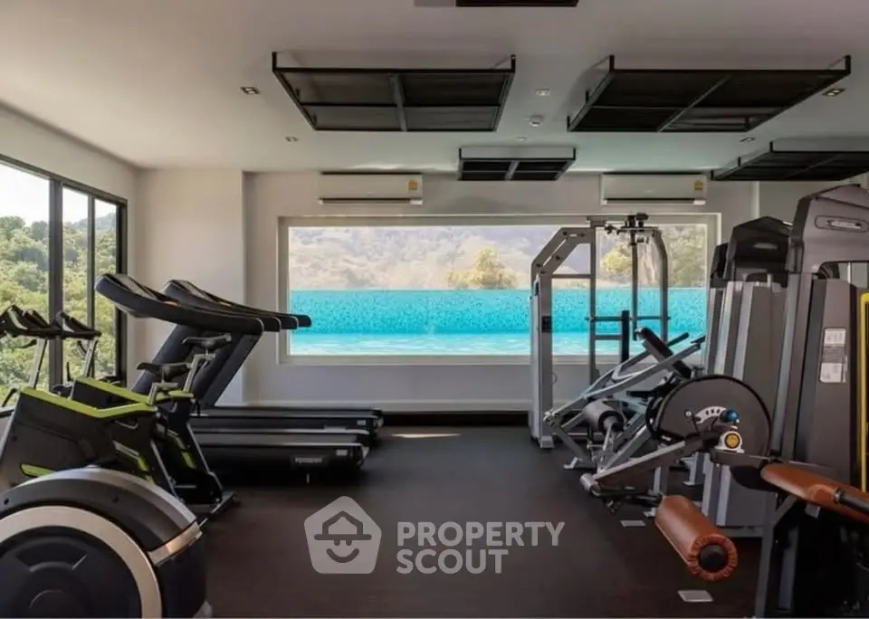 Luxurious gym with modern equipment and stunning pool view in upscale real estate property.