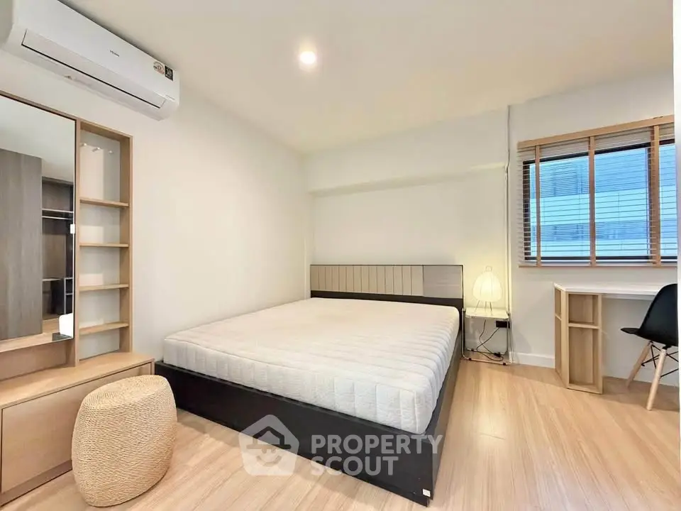 Modern bedroom with minimalist design, featuring a large bed, wooden flooring, and ample natural light.