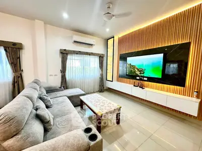 Modern living room with stylish decor, large TV, and comfortable seating in a bright, airy space.