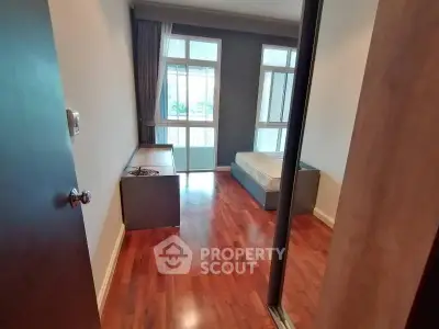 Spacious bedroom with wooden flooring and large windows for natural light.