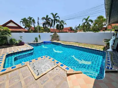 Stunning backyard pool with unique dolphin tile design and lush tropical landscaping.