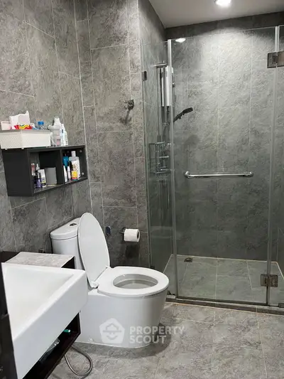 Modern bathroom with glass shower and sleek gray tiles