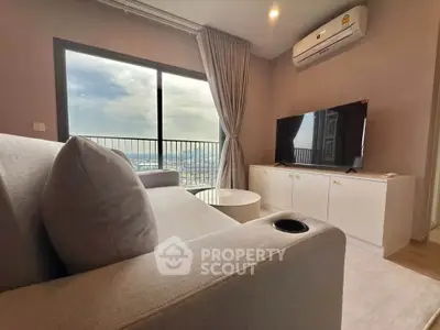 Modern living room with large window and city view, featuring cozy sofa and sleek TV setup.