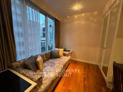 Cozy living room with elegant sofa and large window offering city view