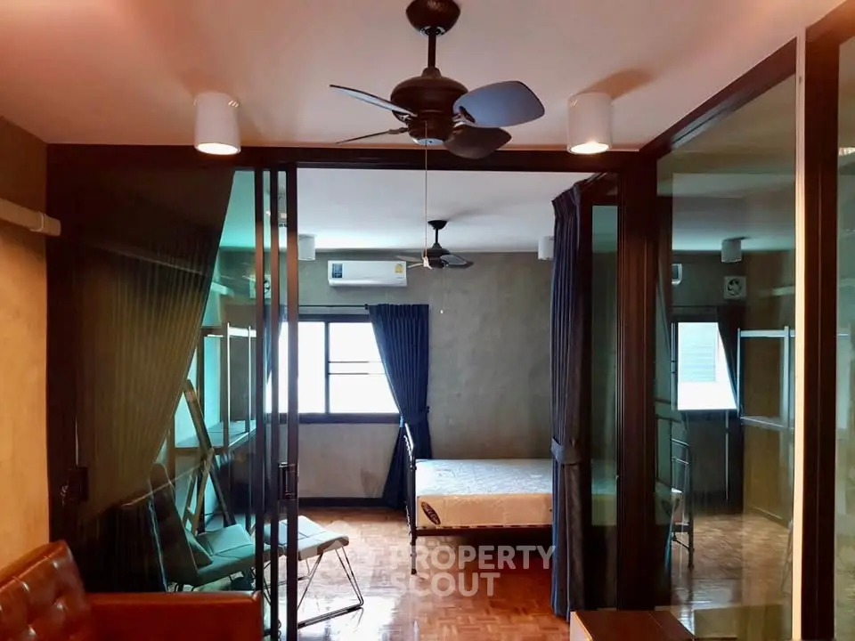 Spacious bedroom with modern ceiling fan and large windows for natural light.