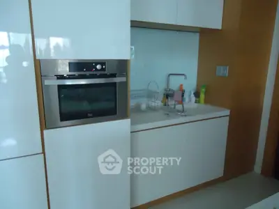 Modern kitchen with sleek white cabinets and built-in oven, perfect for contemporary living.
