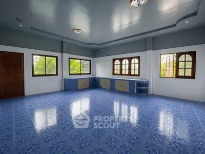 Spacious blue-tiled room with large windows and wooden accents, perfect for versatile living space.