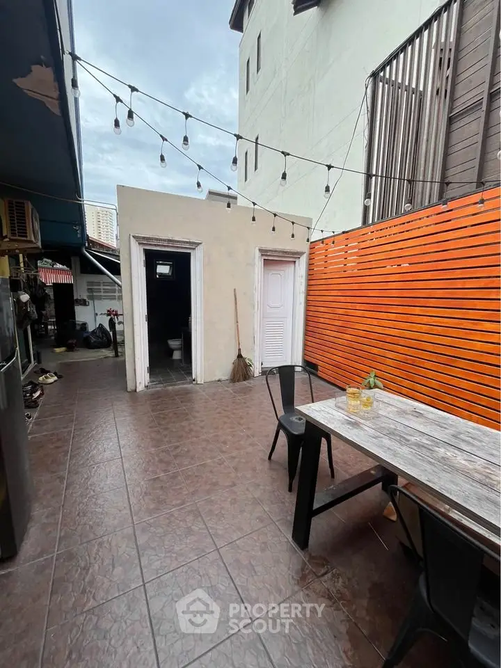 Charming outdoor patio with rustic table and string lights, perfect for entertaining.