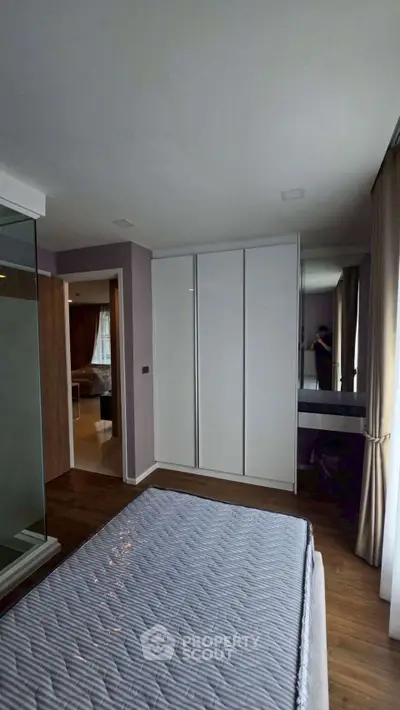 Modern bedroom with sleek wardrobe and large window offering natural light.