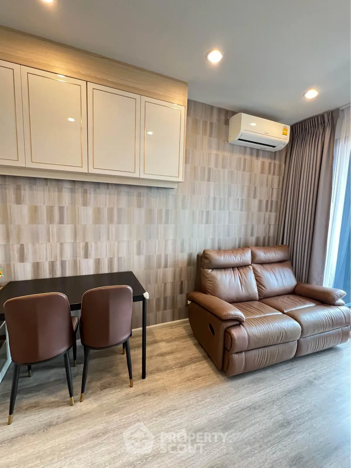 Modern living room with stylish furniture and air conditioning, featuring a cozy leather sofa and elegant dining area.