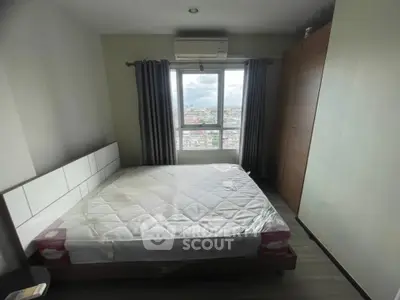 Modern bedroom with large window offering city view, featuring a comfortable bed and ample closet space.