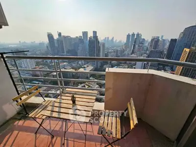 Stunning cityscape view from a high-rise balcony with cozy seating area.
