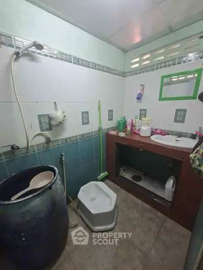 Compact bathroom with traditional squat toilet and shower in a tiled setting.