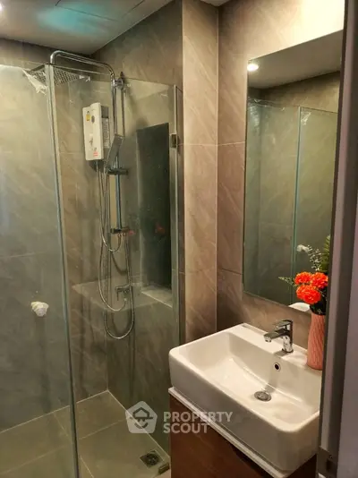 Modern bathroom with glass shower and stylish sink in contemporary apartment.