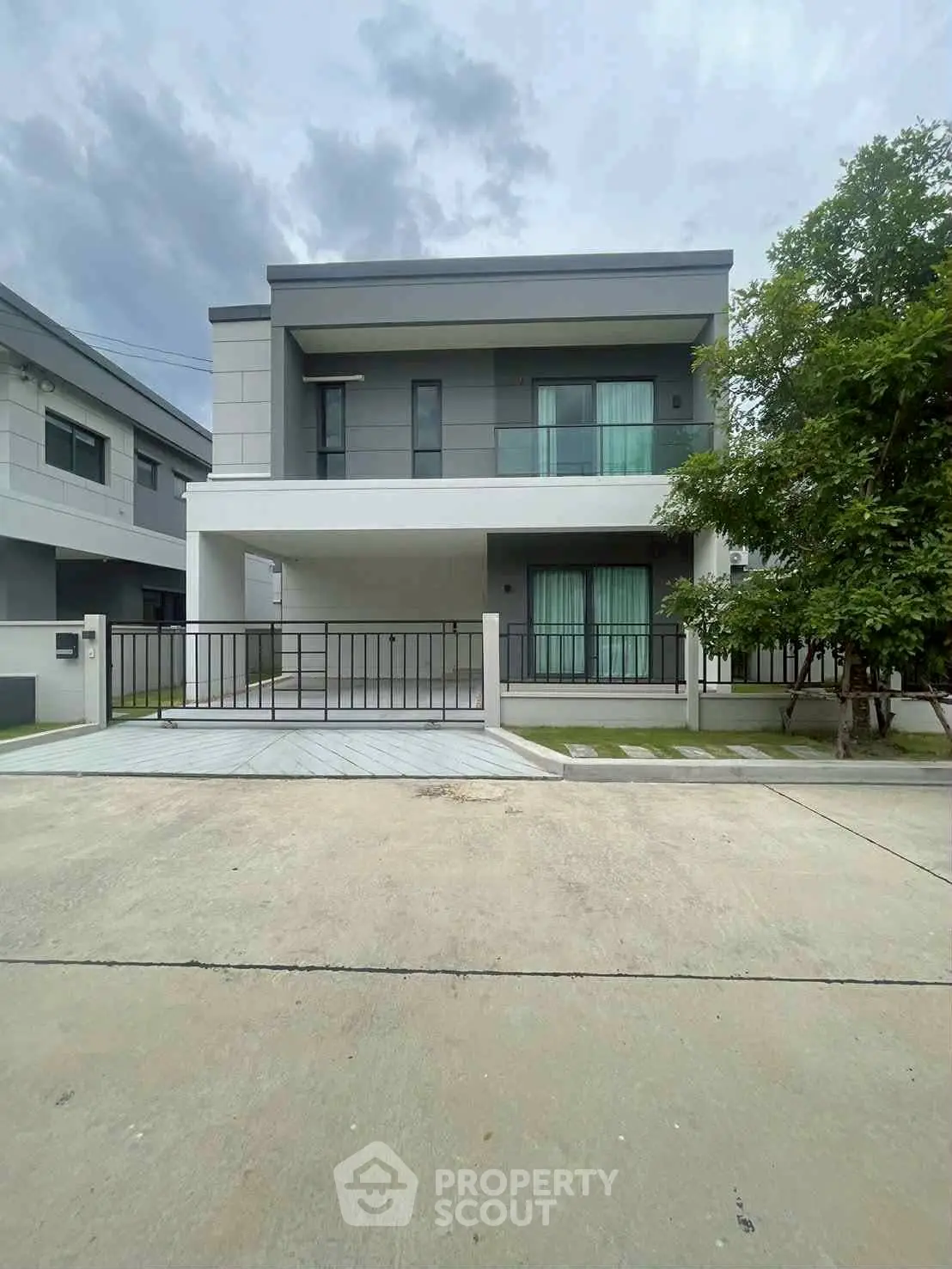 Modern two-story house with sleek design and spacious driveway in suburban neighborhood.