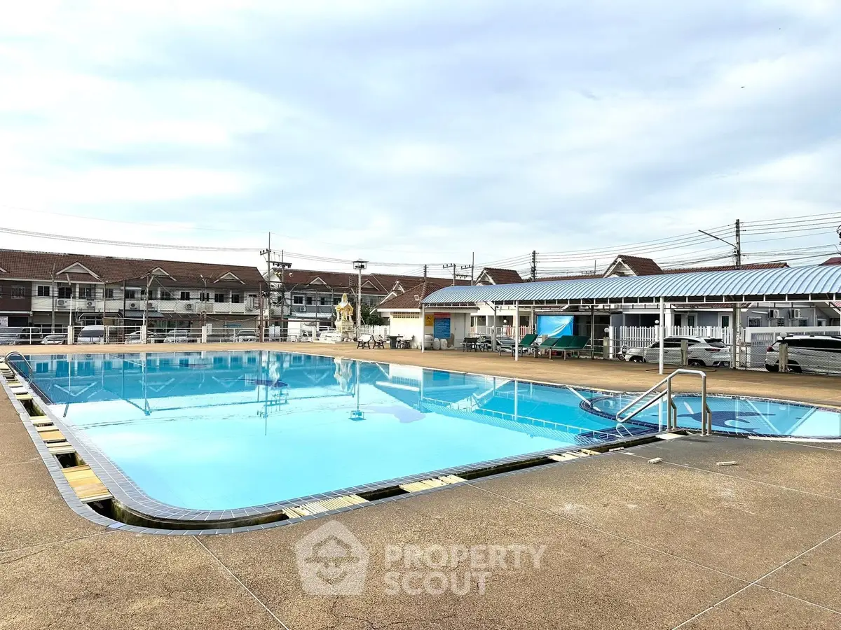 Spacious outdoor pool area in residential complex with clear blue water and surrounding amenities.