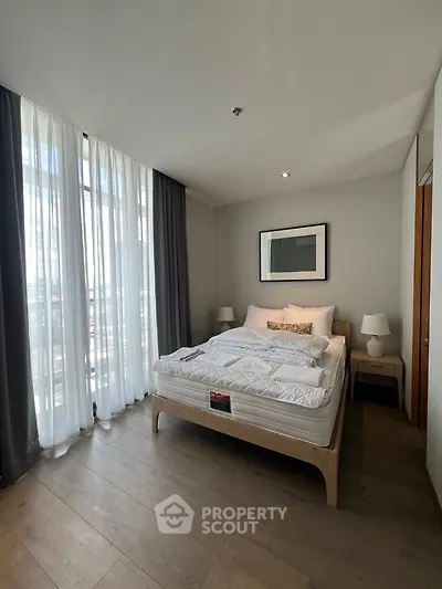 Modern bedroom with large windows and stylish decor in a luxury apartment.